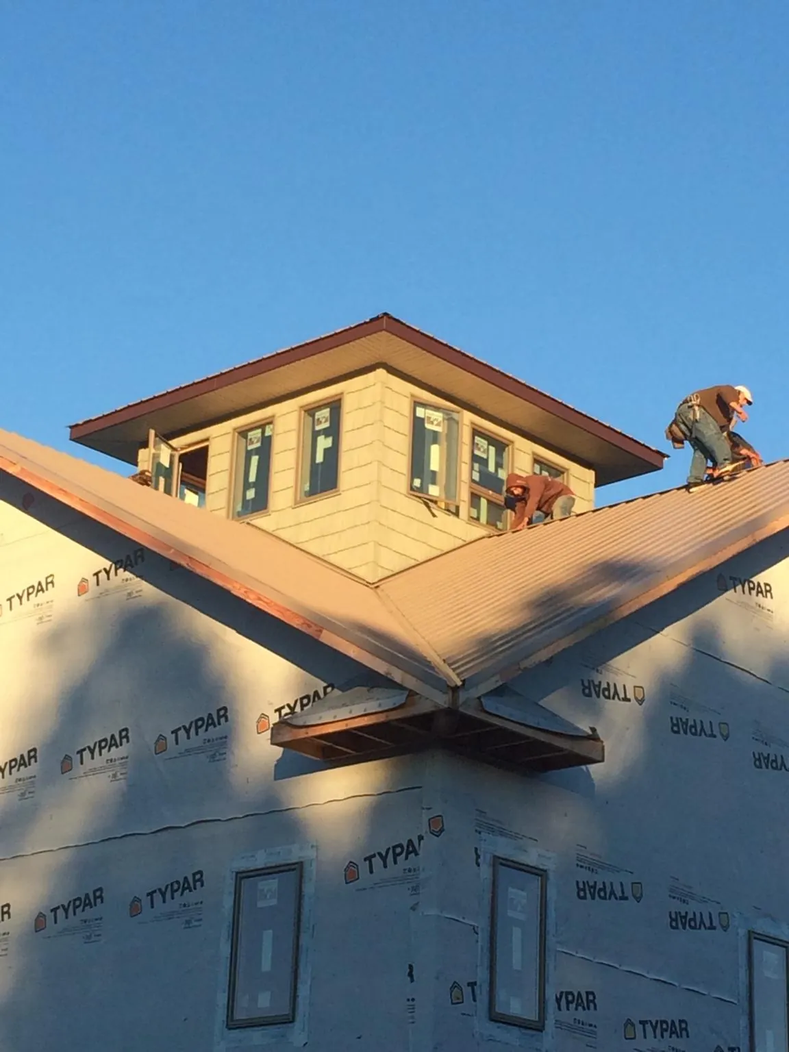 Roofers working around a rooftop cupola on a new metal roof at sunset — Roof Waterproofing in Windham by Roofing Brothers
